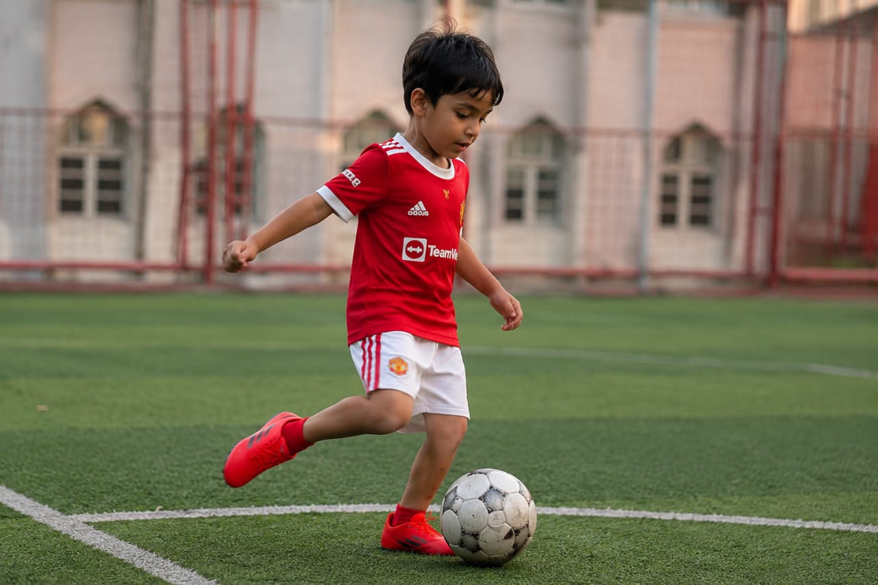 Young child developing football skills during a First Kick Academy session